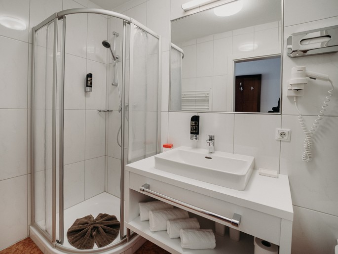 Helles Badezimmer mit Dusche, Waschbecken und Fön